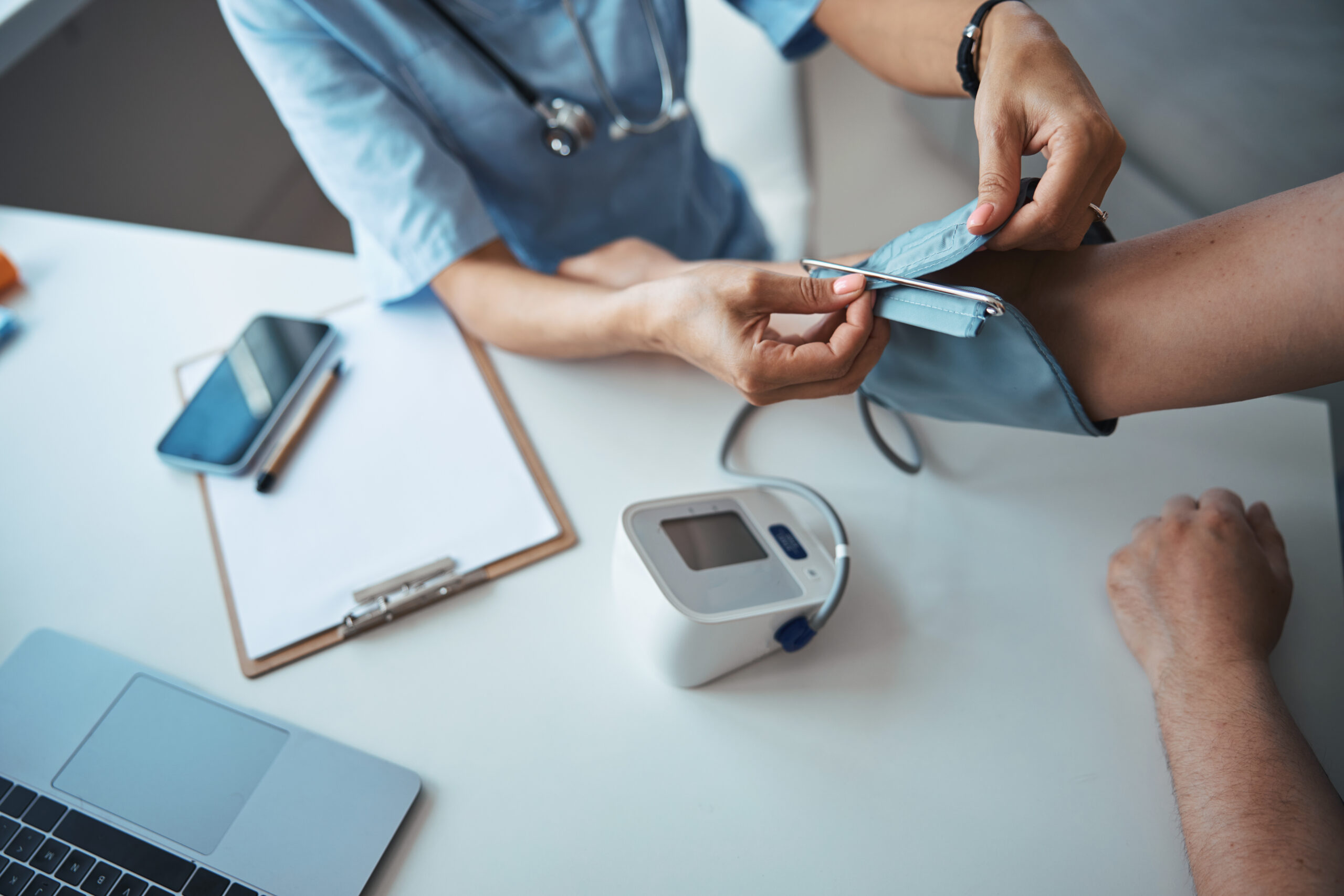 female doctor checking patient blood pressure in clinic e1682348846289
